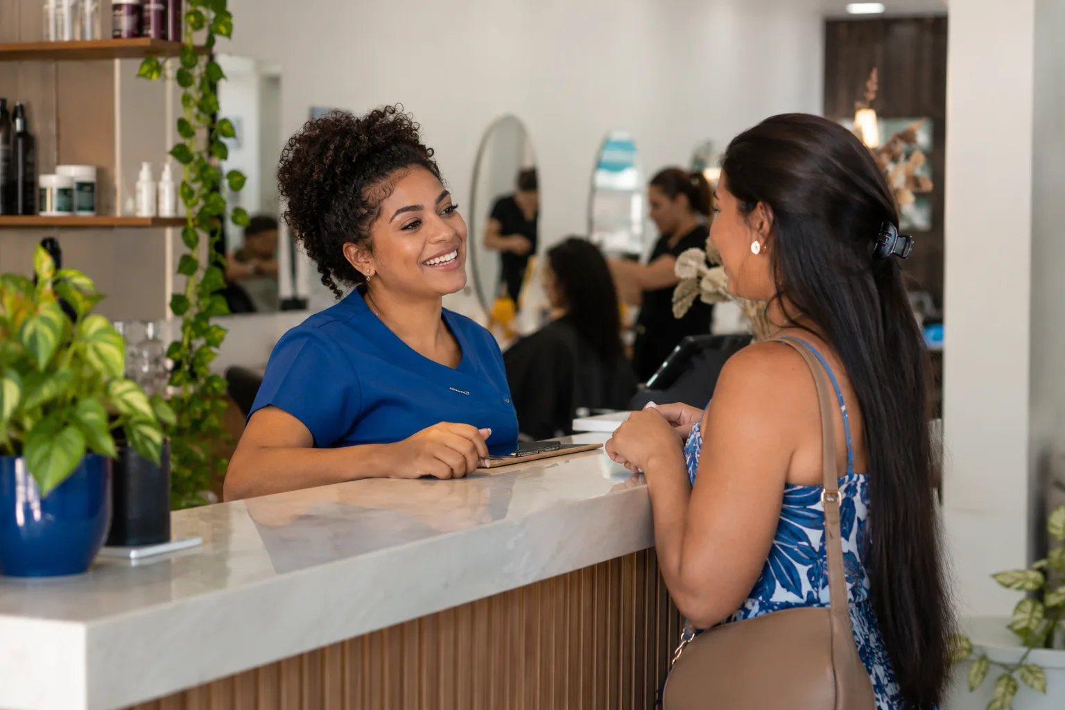 Recepcionista de salão de beleza conversa com uma cliente no balcão