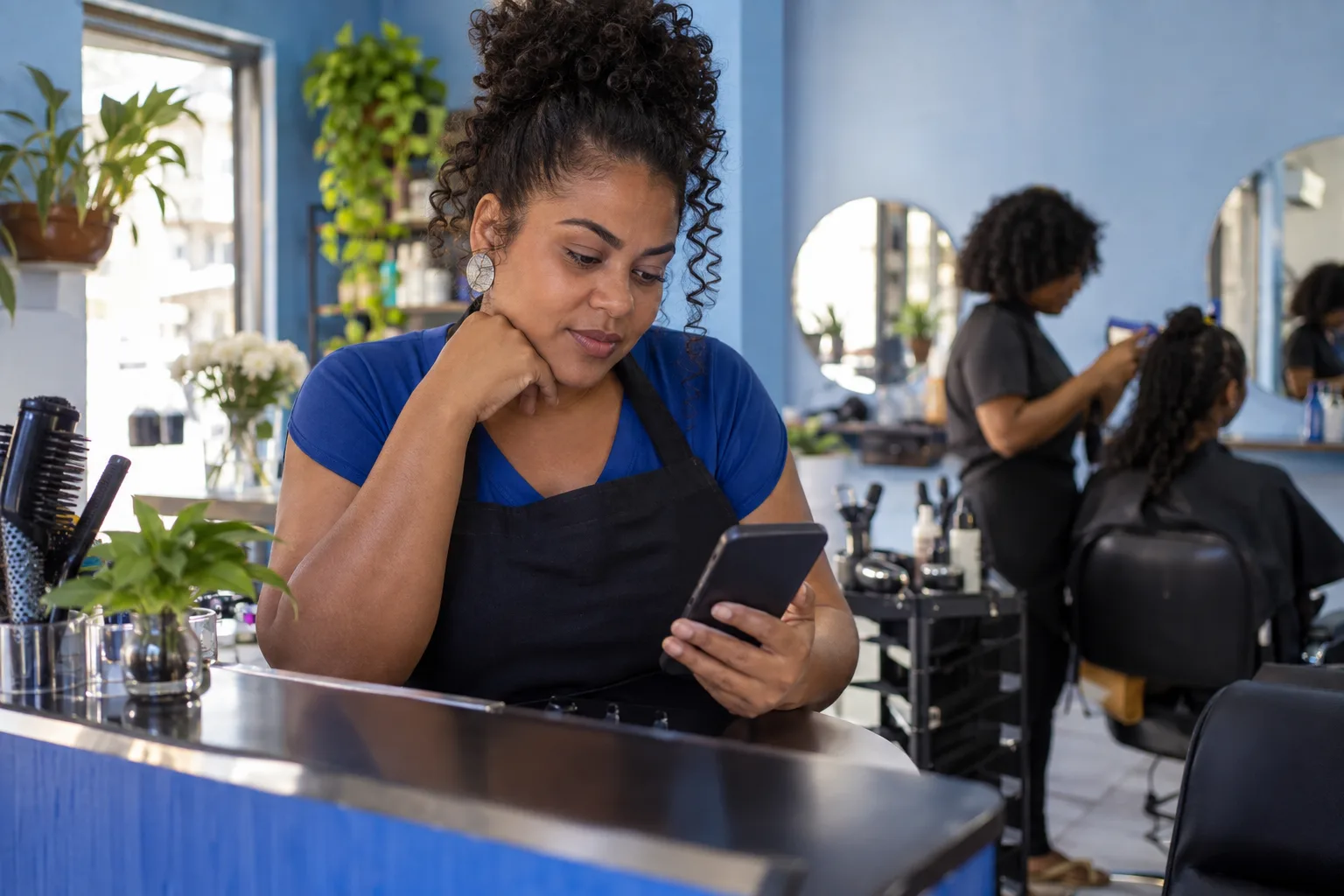 Dona de salão de beleza confere no celular o prazo da declaração anual no balcão do estabelecimento
