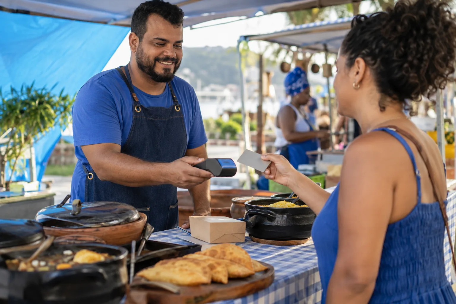Microempreendedor vende comida caseira em barraca de feira e recebe no cartão