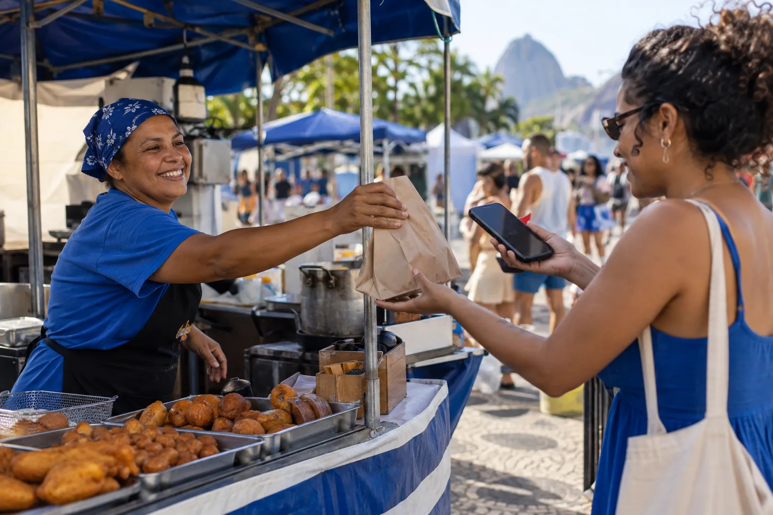 Vendedora de comida em feira entrega pedido a cliente que paga pelo celular