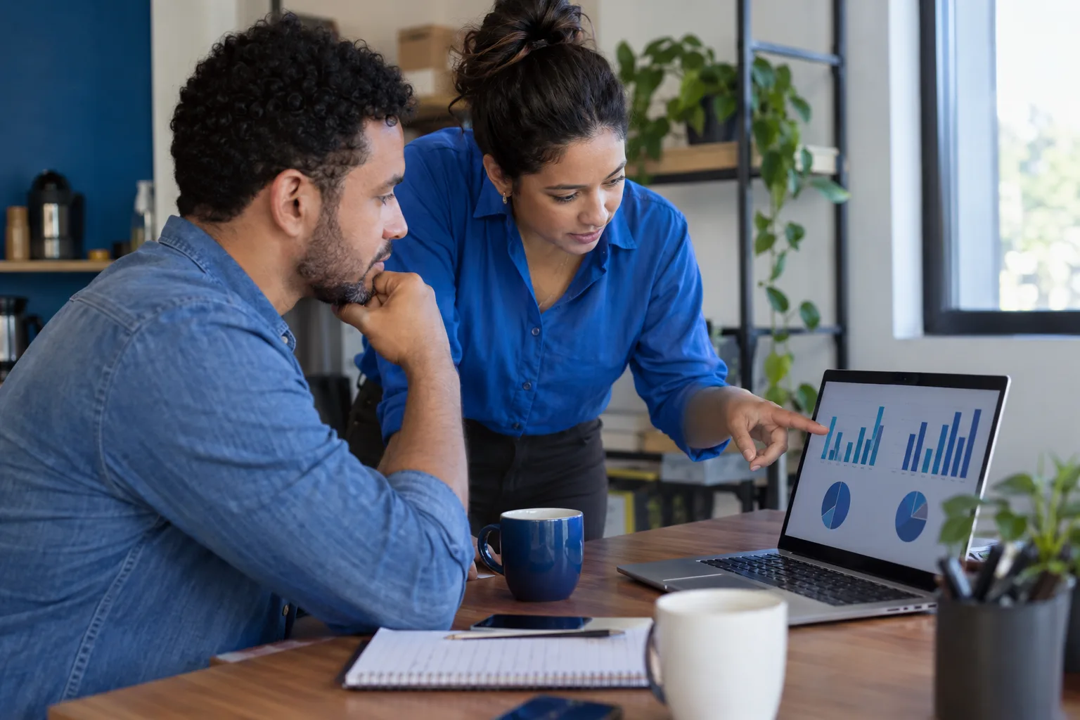 Dois colegas comparam no notebook o estoque de duas filiais da empresa
