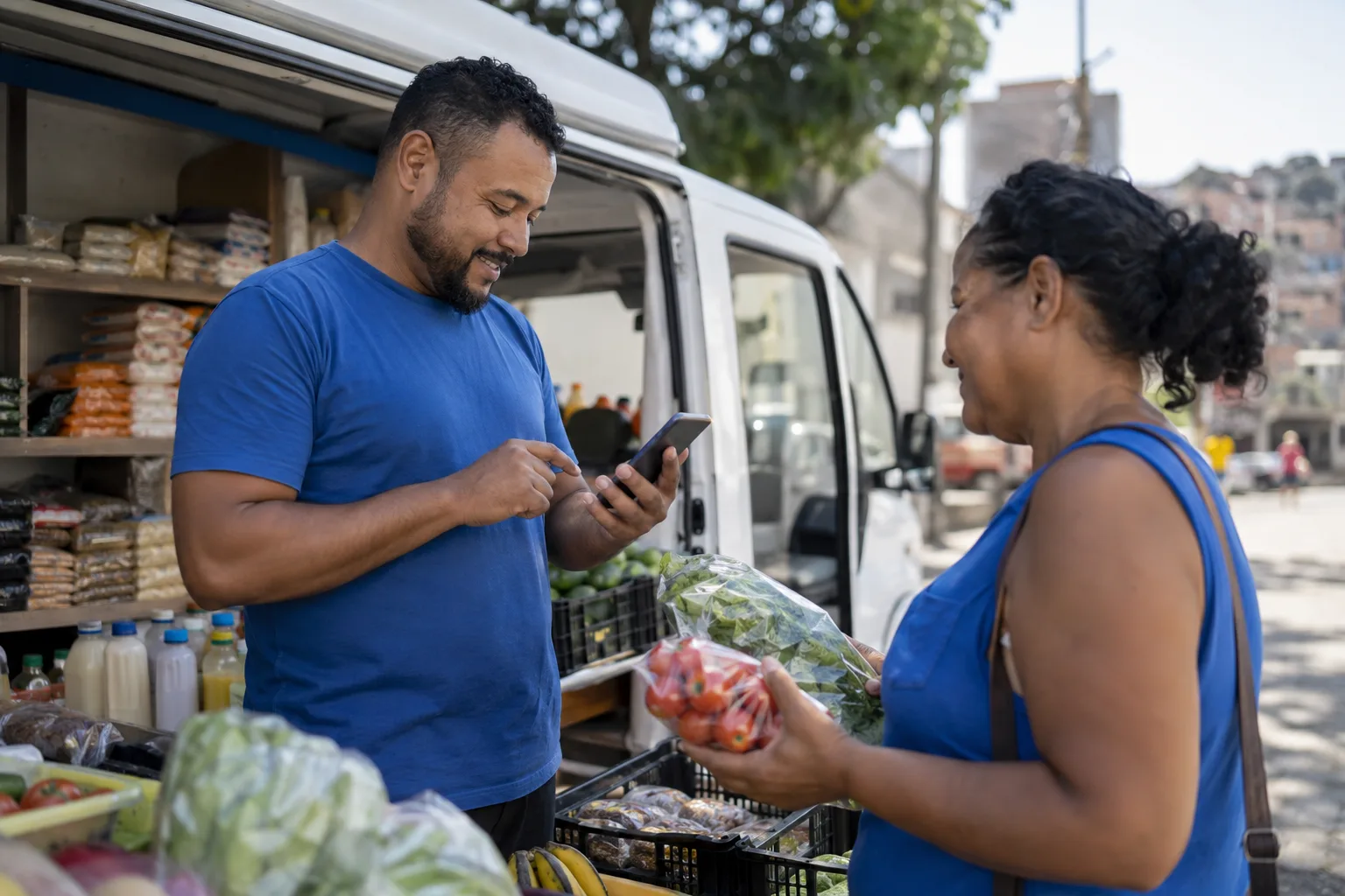 Vendedor registra uma venda no celular ao lado da van com produtos