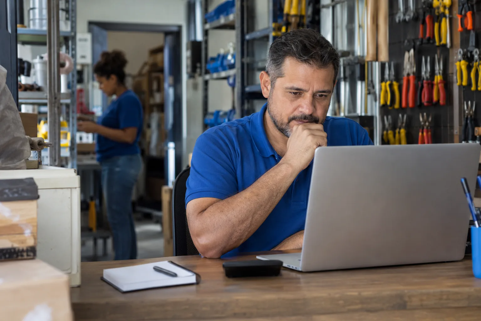 Dono de loja de ferragens analisa custos dos produtos no notebook no escritório dos fundos