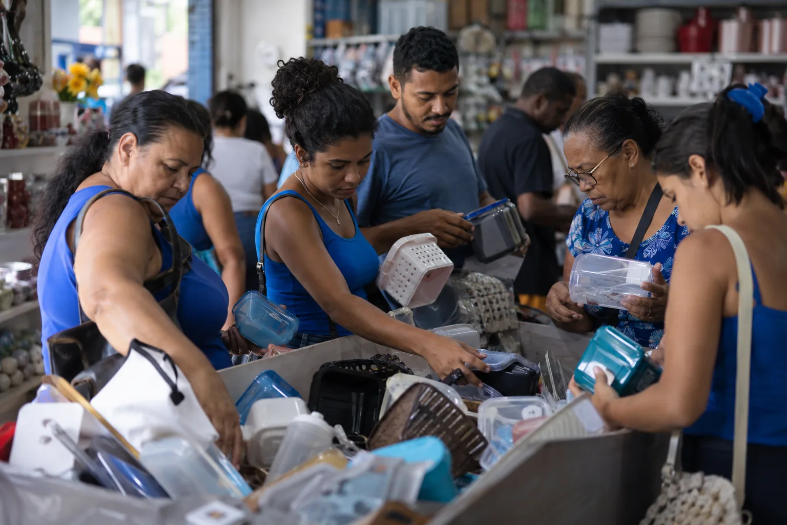 Clientes escolhem produtos em cesto de queima de estoque numa loja de bairro
